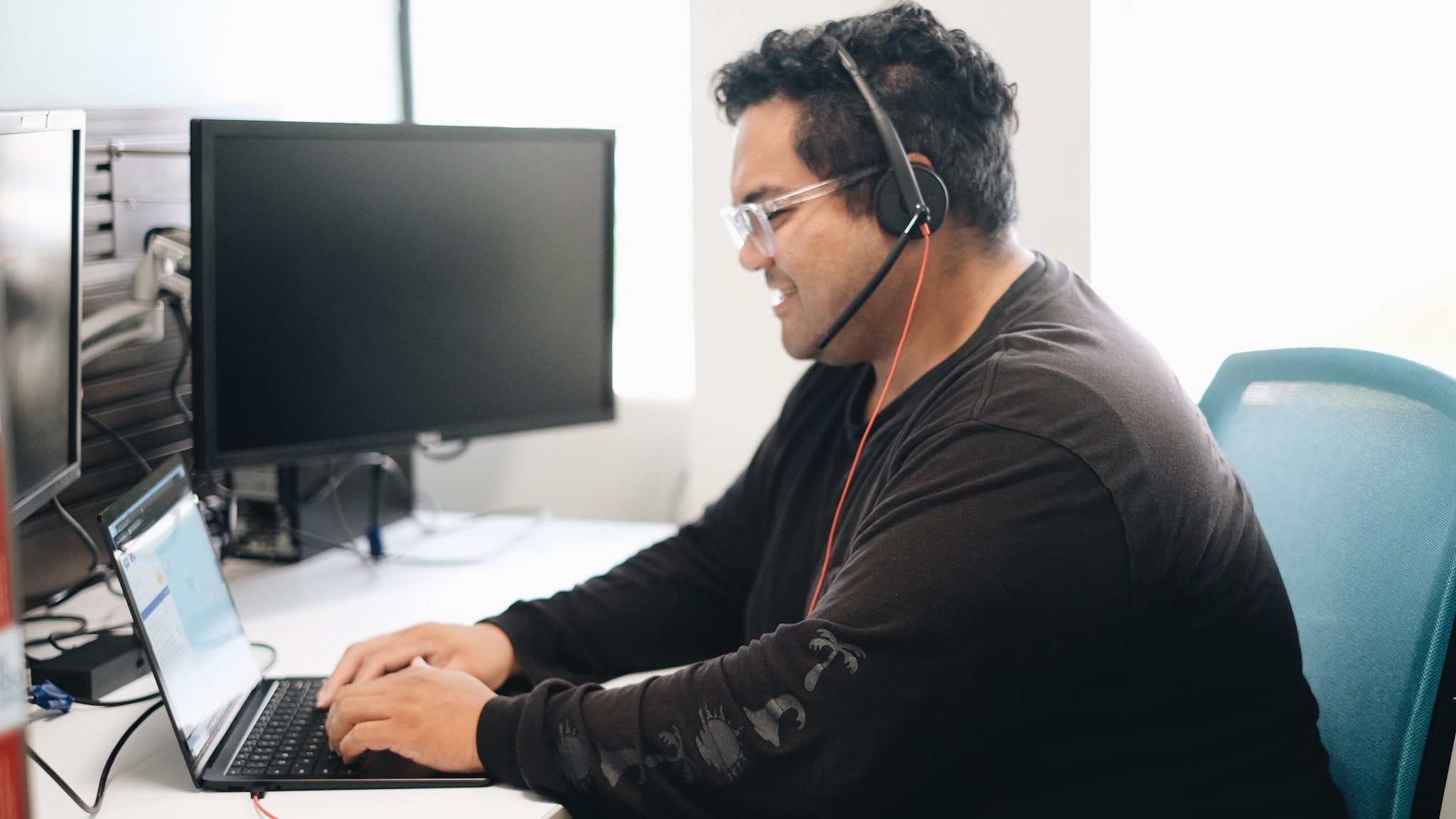 SUD Care Coordinator na may suot na headset na nagta-type sa isang laptop